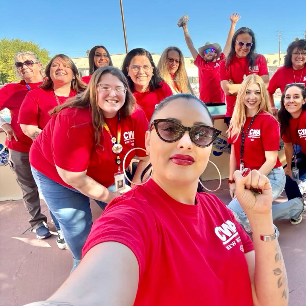 Group of people wearing red "CWA New Mexico" t-shirts posing for a selfie outdoors.
